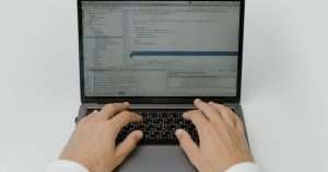 A person working on a cloud computing project with a laptop and coding tools