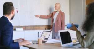 Person at a laptop with infrastructure diagrams sketched on a whiteboard in a modern office