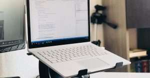 Laptop and external monitor on a compact home desk with notepad and small network device for hands-on lab practice