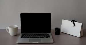 person at a tidy desk using a laptop and notebook while reviewing training options