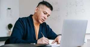 Person studying on a laptop in a tidy home office with notebook and coffee
