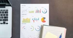 workspace with a laptop, printed charts and a notebook for analytics