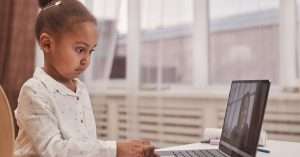 Person at a desk using a laptop for a virtual DevOps training session with notes and a headset