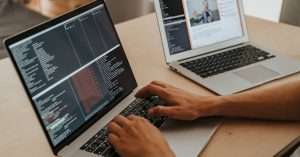A developer sitting at a desk using a laptop with code on the screen
