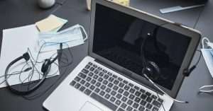 A professional in an office setting providing IT support on a laptop