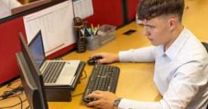 An office worker analyzing data on a laptop with Excel open.