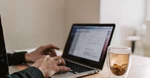 A person working on a laptop at a modern desk in a home office.