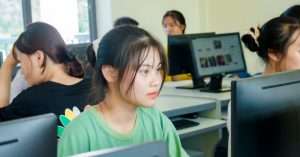 A student focused on a laptop while studying in a modern office setting
