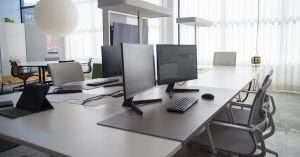 A busy office workspace with a laptop, documents, and a person analyzing Excel data.