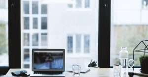 A modern office workspace featuring a laptop and notepad on a desk.