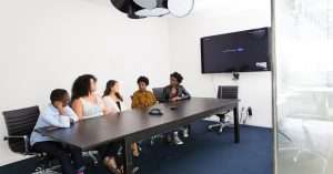 A diverse team discussing strategies in a modern office environment with laptops and tech tools.