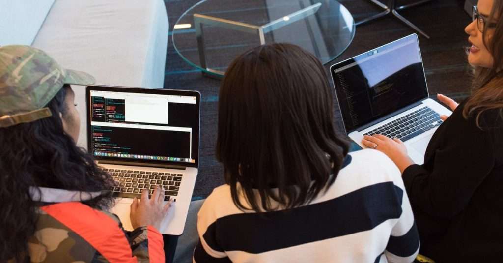 A diverse team collaborating on laptops in a modern office environment.