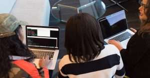 A diverse team collaborating on laptops in a modern office environment.