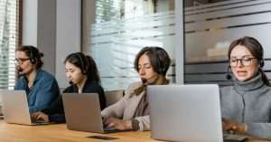 A busy helpdesk workspace with technicians assisting users on laptops