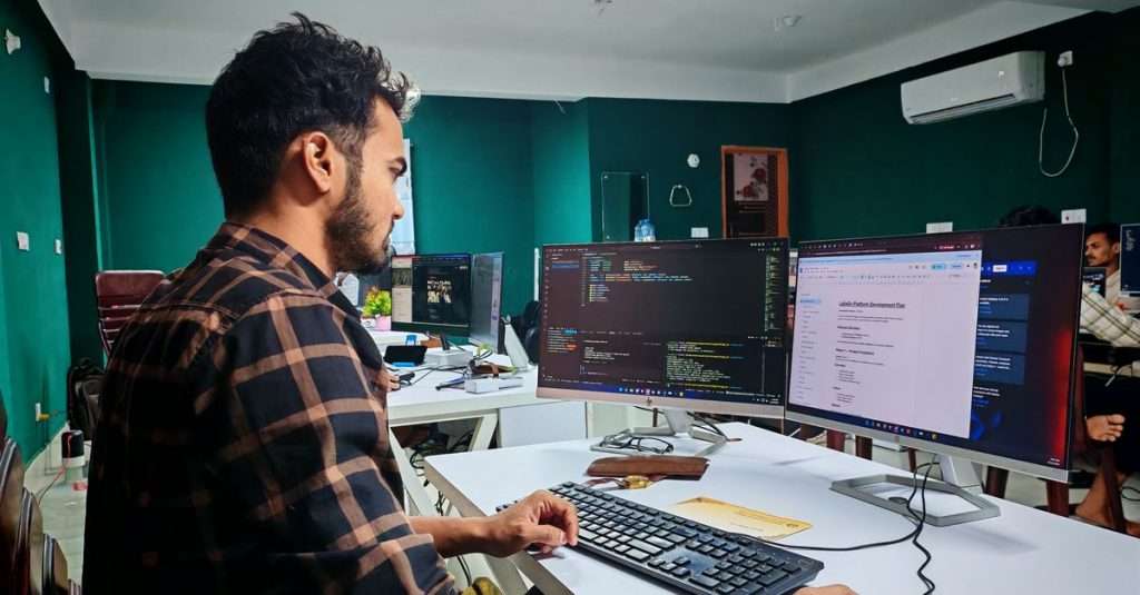 A software developer working at a laptop in a modern office.