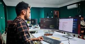 A software developer working at a laptop in a modern office.