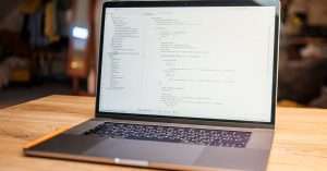 A modern workspace featuring a laptop, notepads, and coding materials