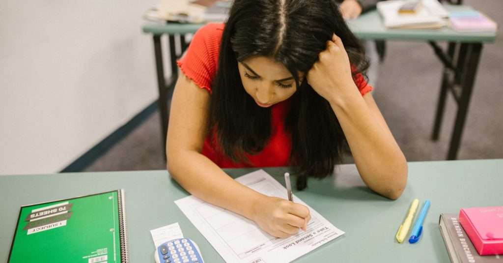 a student reviewing notes and using a laptop for IT exam preparation