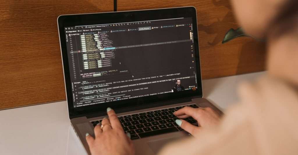 A programmer working on debugging code at a laptop in an office setting