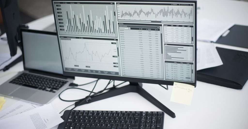 A data analyst working on a laptop in a modern office environment.
